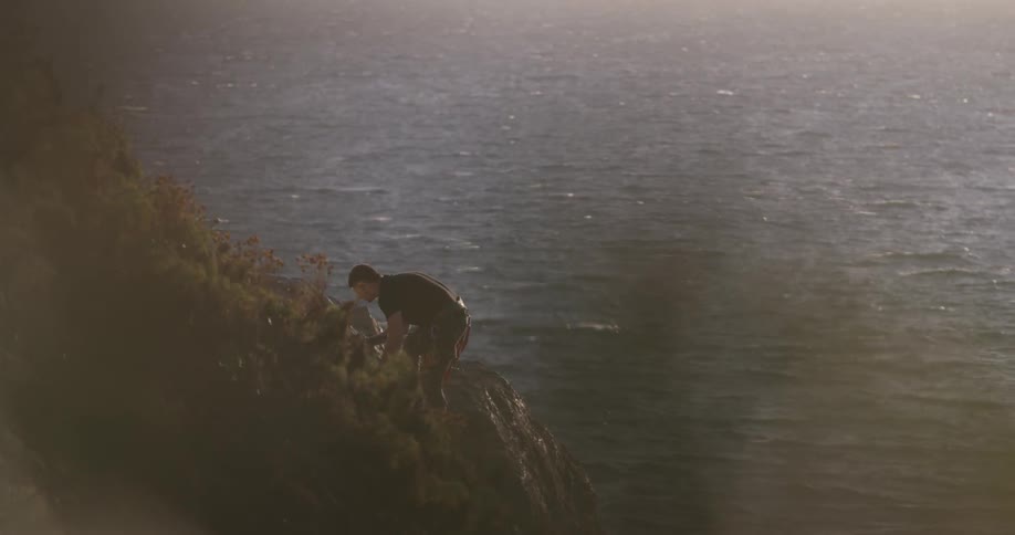 Man climbing up a cliff next to the sea