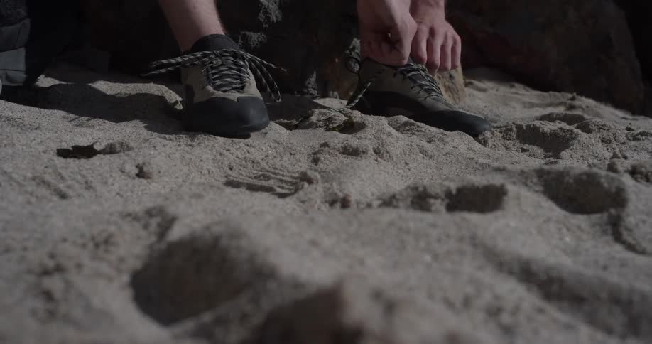 A person that is tying their shoes on the beach