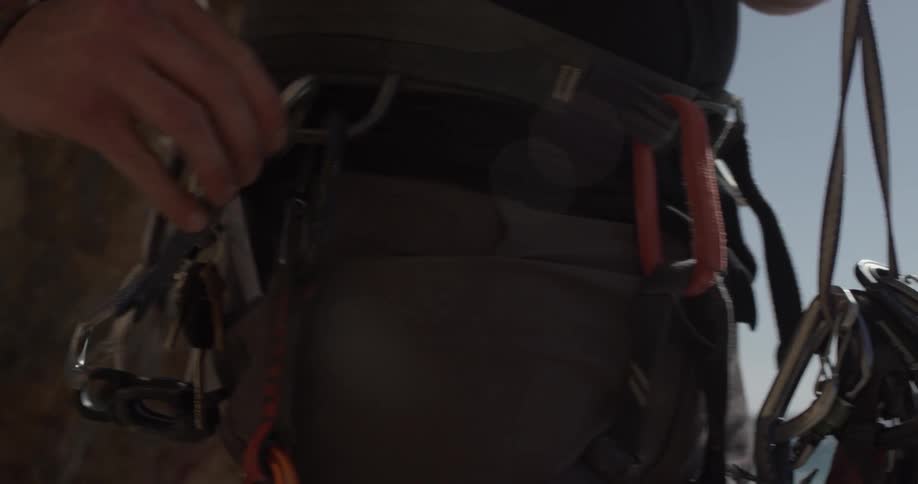 A person is moving clips to their belt harness