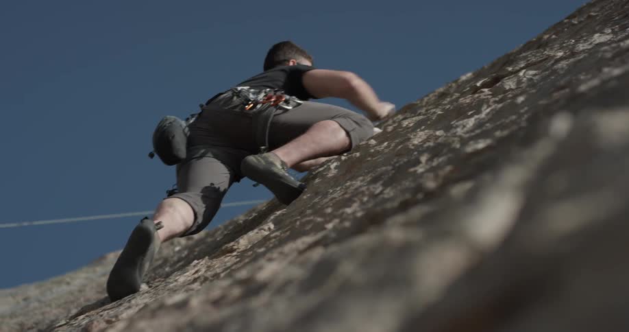 A man gaining his footing climbing up a cliff