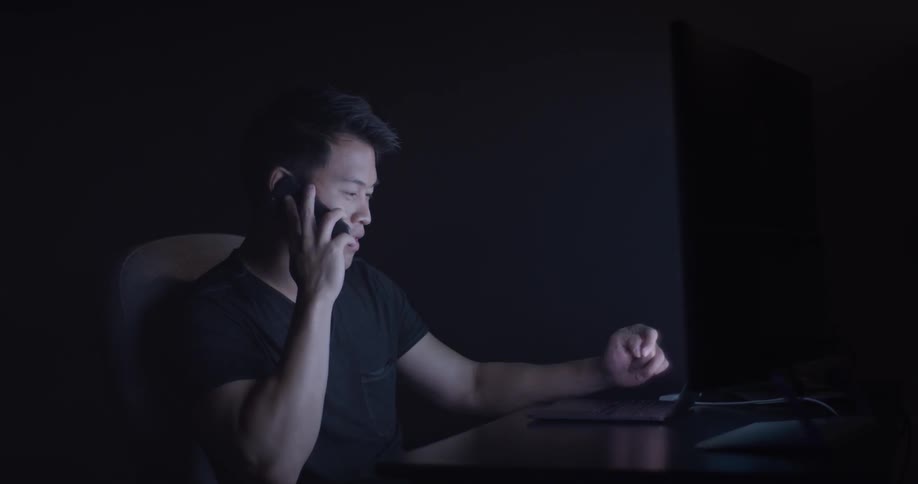 A man at a desk is talking on a cell phone