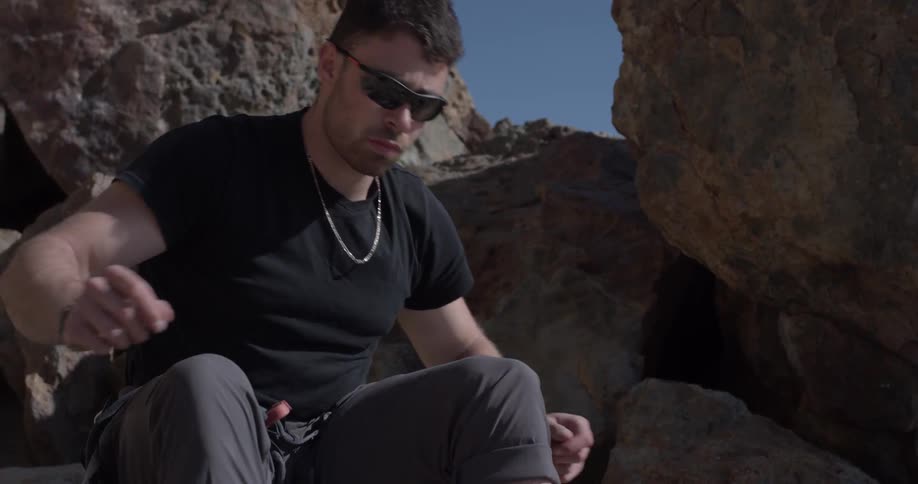 Man sitting tying shoes on rocks
