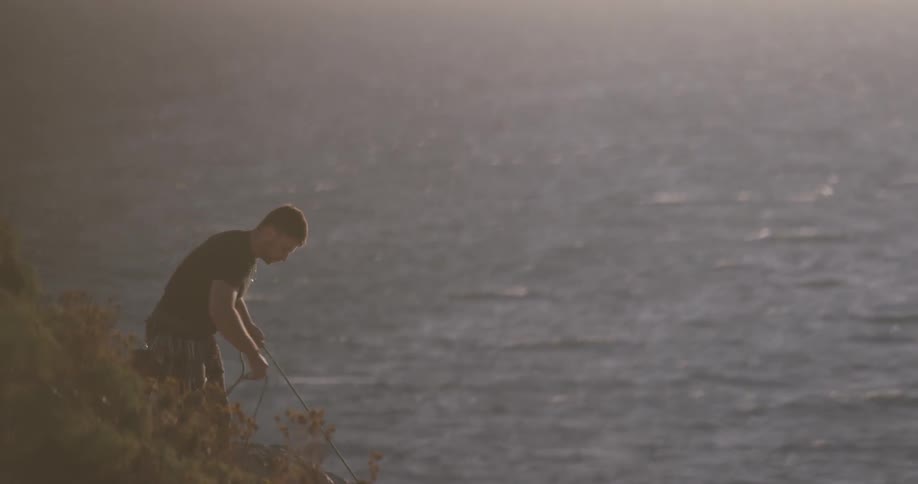A person that is holding a rope next to the sea