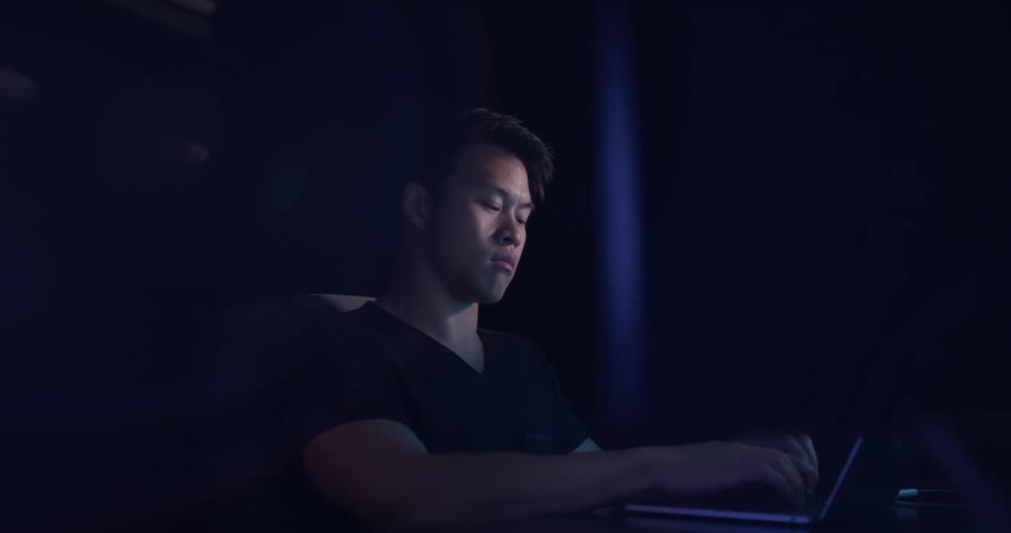 A man is typing on a laptop indoors