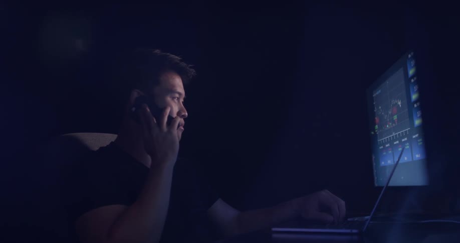 A man talking on a phone while working at a computer
