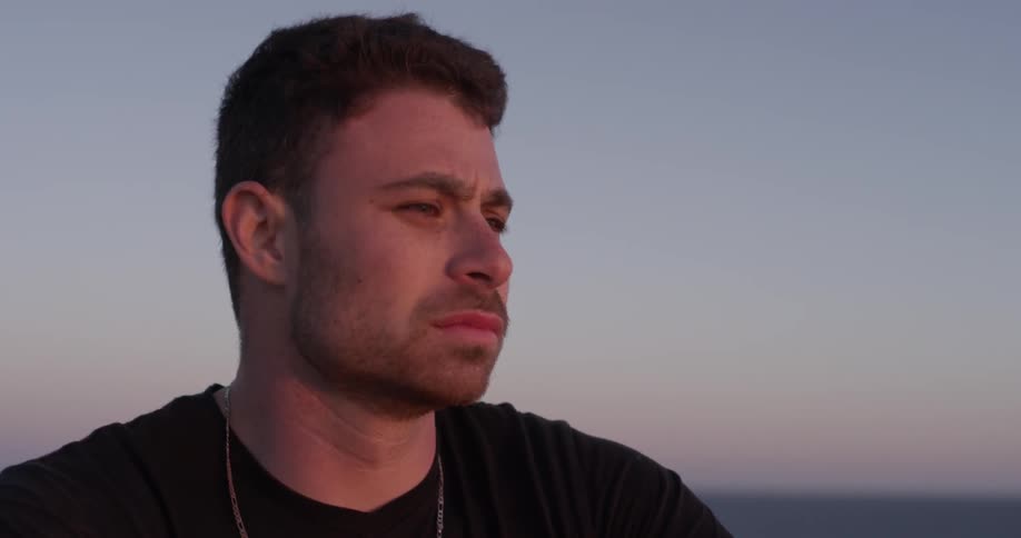Sad that the day is coming to an end the young man looks out over the horizon