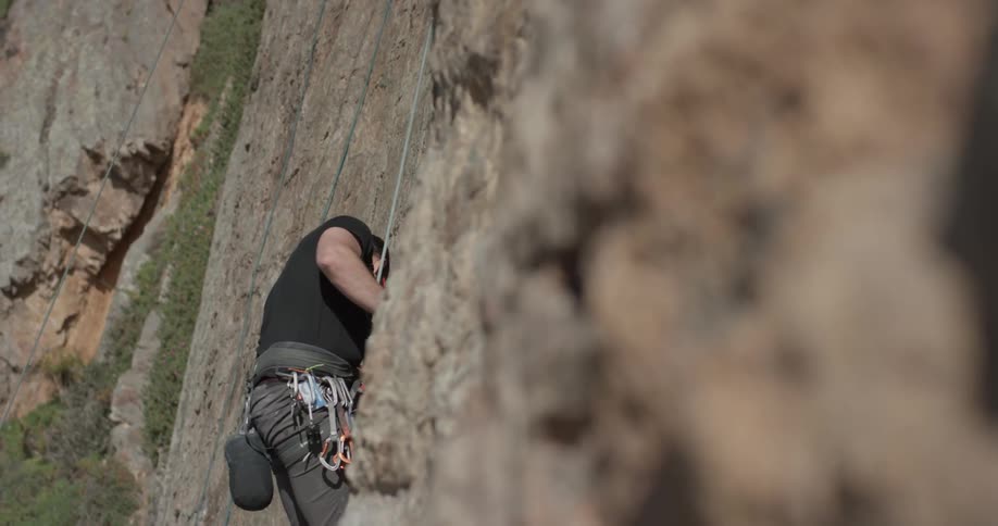 A man that is climbing up a rock wall with ropes