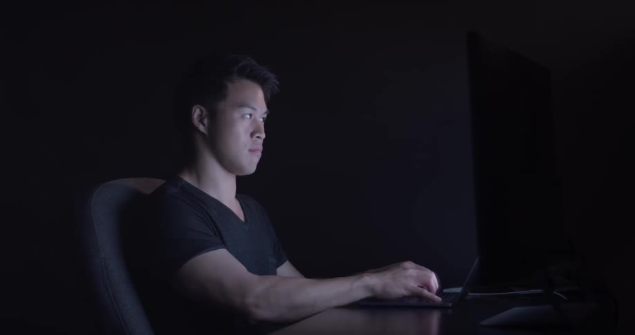 Man sit at desk looking at monitor and typing