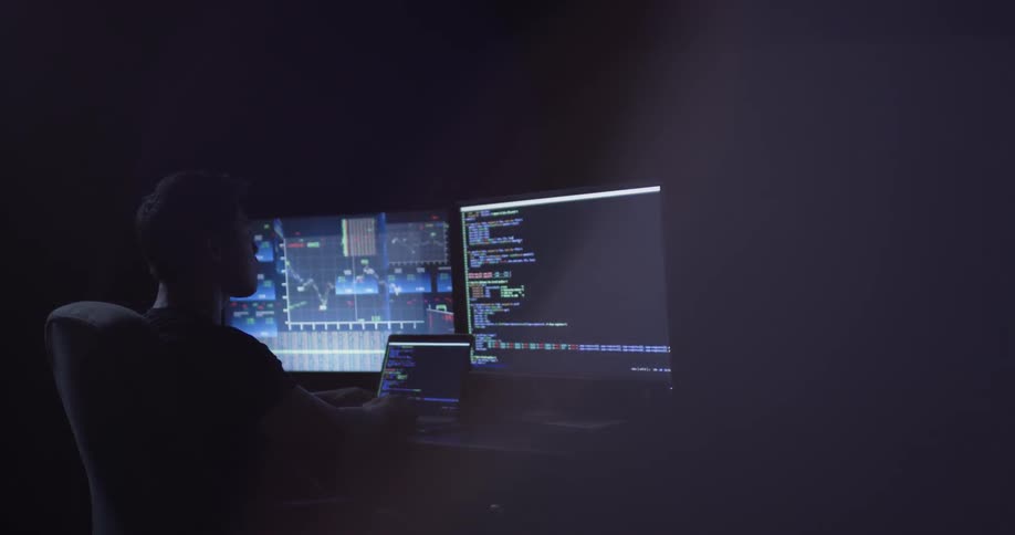A man sitting in a dark office looking at a computer