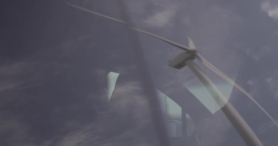 Man Driving Electric Car Through Wind Farm