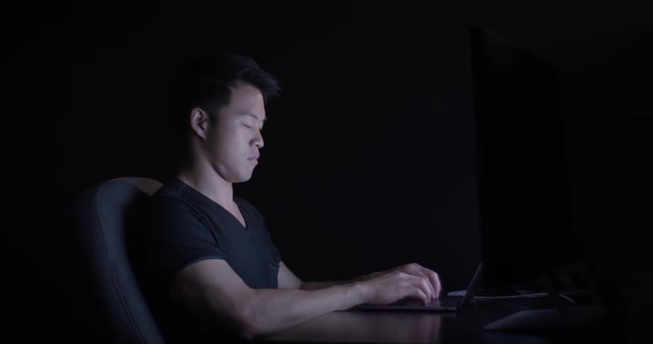 A man sitting at a desk typing on a laptop
