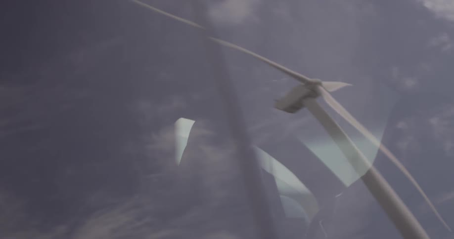 A windmill that is rotating in the reflection of a car window
