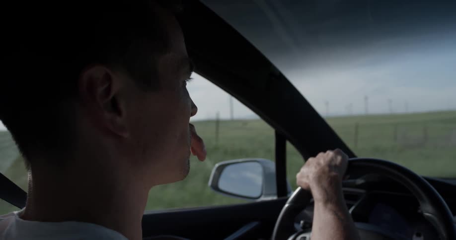 A man drives a car down a rural road