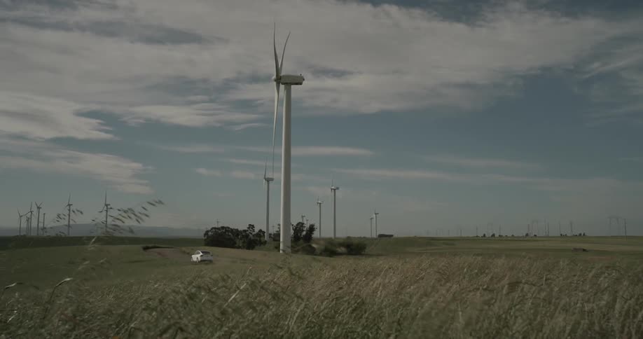A car drives past a wind turbine