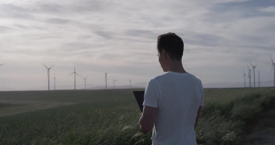 Man Driving Electric Car Through Wind Farm