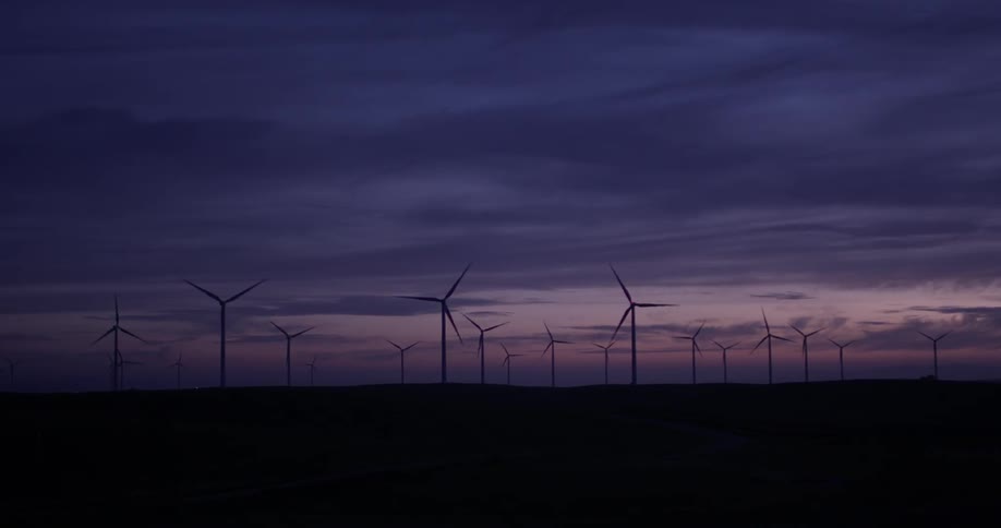 Wind turbines turning against a dark sky