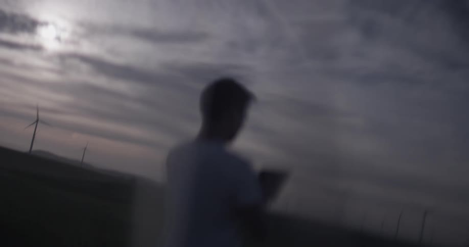 A man monitors windmills with a tablet outdoors