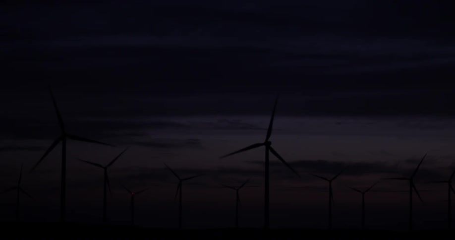 Some windmills rotating at night on a field