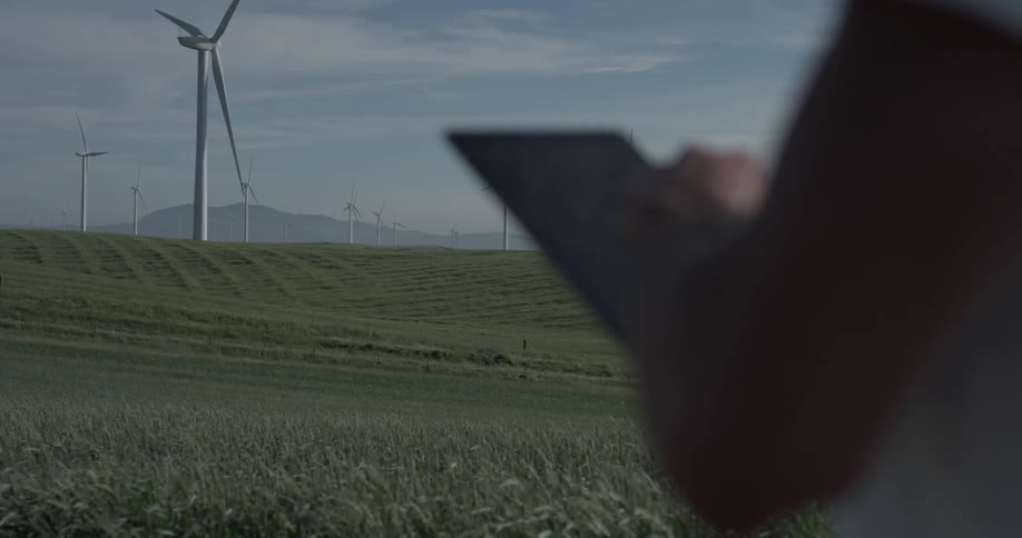 Man Driving Electric Car Through Wind Farm