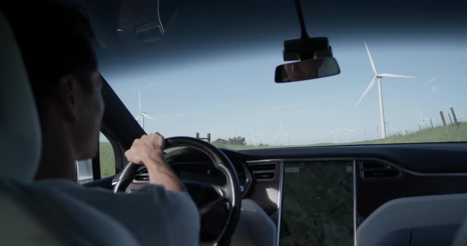 Sun shines thought his windows as the oriental man drives down the country road