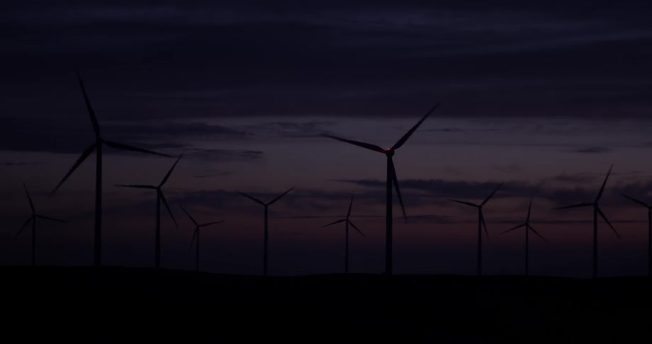 Windmills on a wind farm spin around at sunset