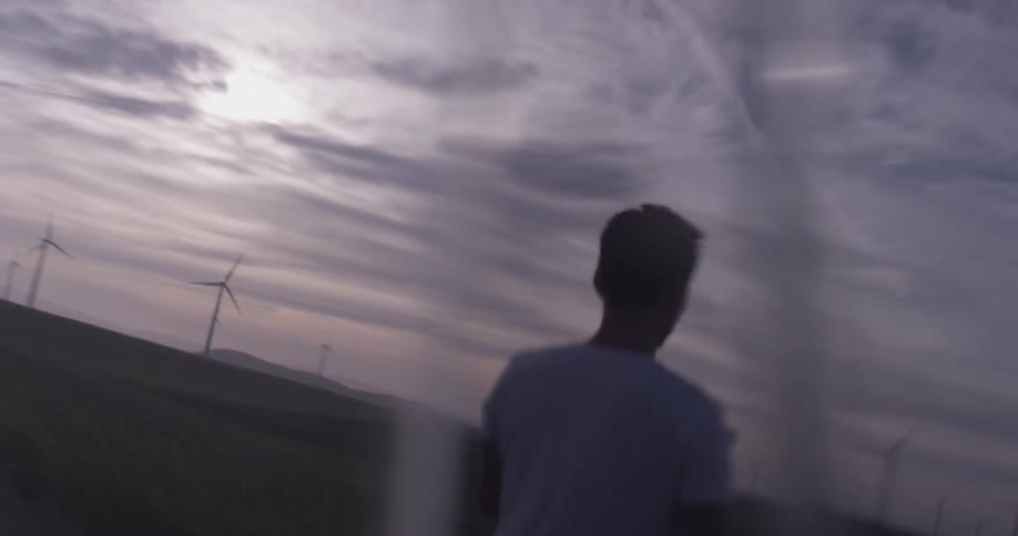 A man walking around a field at dusk carrying a tablet