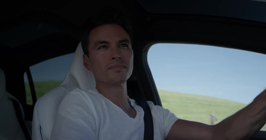 A young man enjoys the mid day view as he drives along