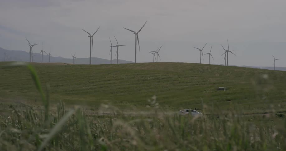 Man Driving Electric Car Through Wind Farm