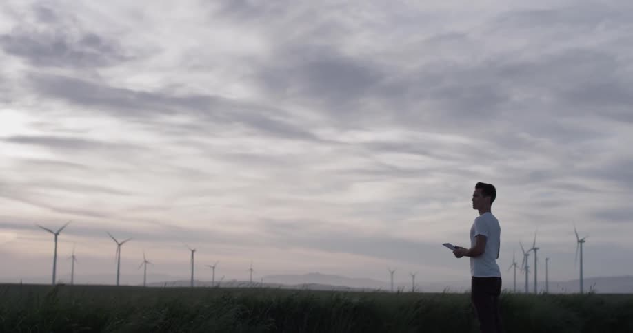 Man Driving Electric Car Through Wind Farm