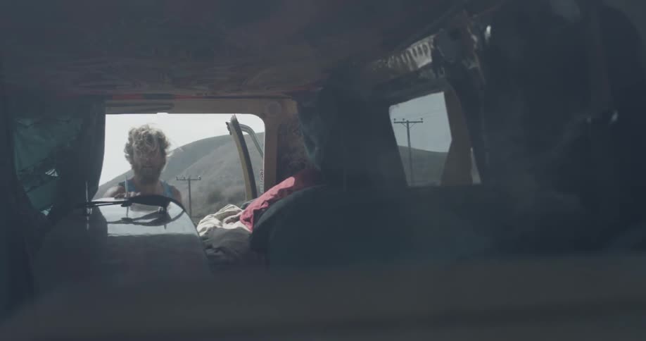 A man putting a surfboard in the back of a van