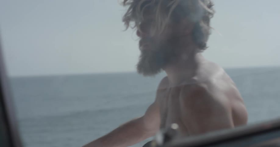 A man carrying a surfboard towards a car
