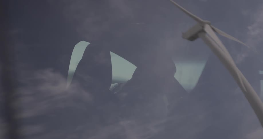 A windmill that is reflected in the window of a car