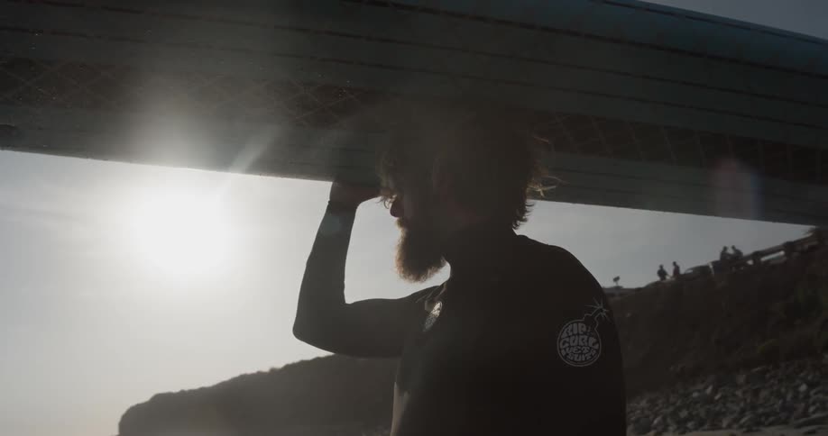 A man carrying a surfboard above his head