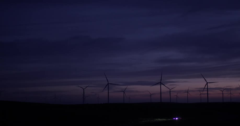 A bunch of windmills rotating at night