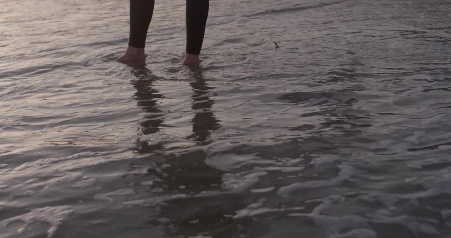 Waves move forward and cover a person's feet