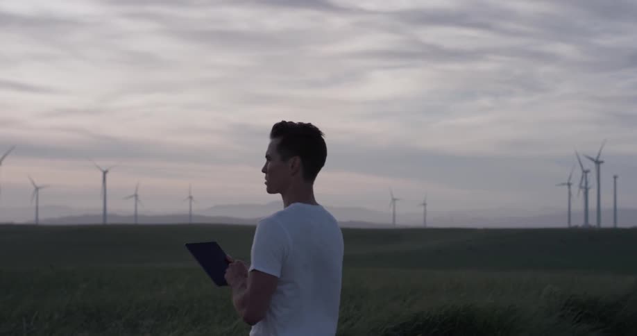 Man Driving Electric Car Through Wind Farm