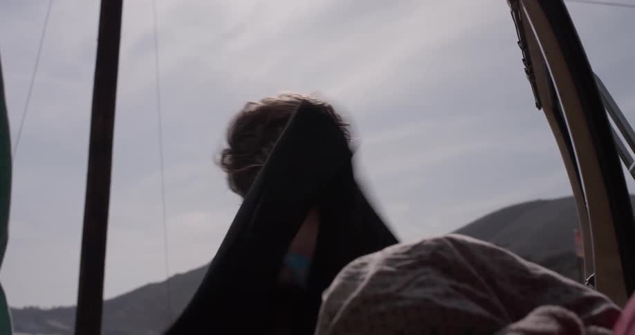 A man hanging up a wetsuit on the back of a car