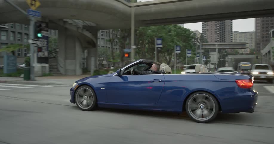 A blue convertible is passed by another car on the street