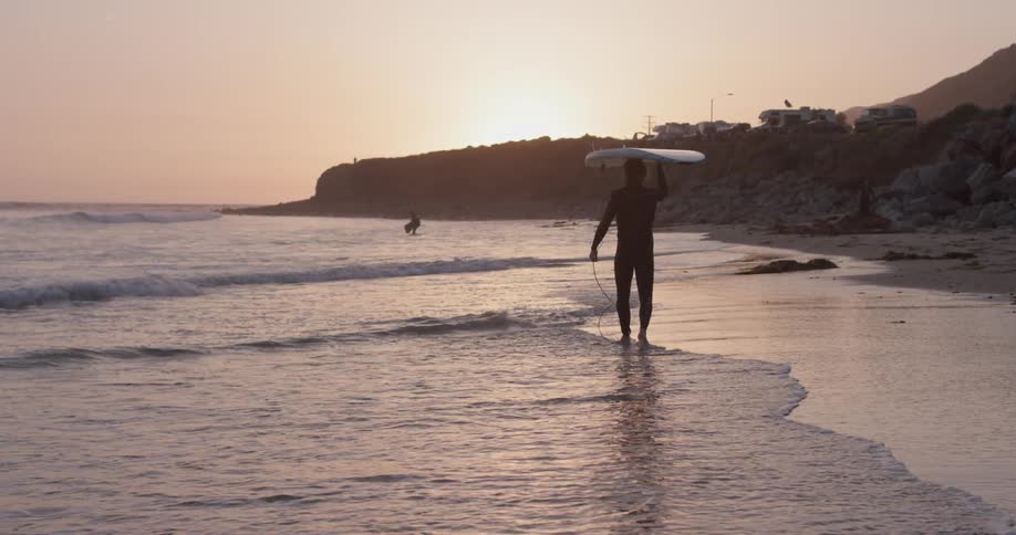 A man carrying a surfboard over his head along the shore