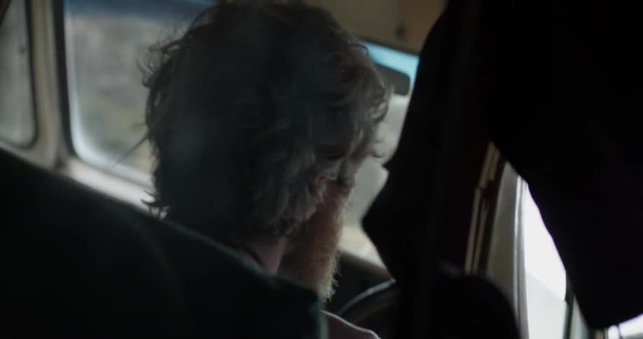 Interior of a bearded man driving down the highway