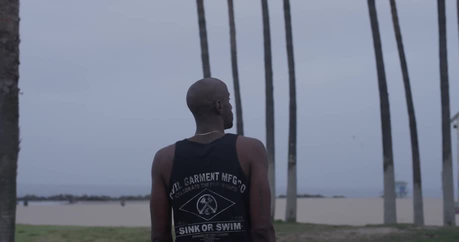 A man is walking in the sand between trees
