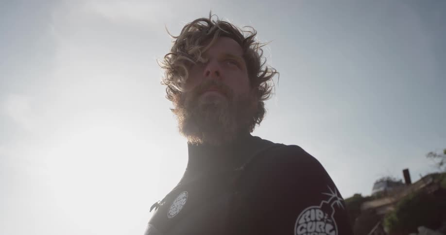 A man in a wetsuit looking into the distance on a sunny day