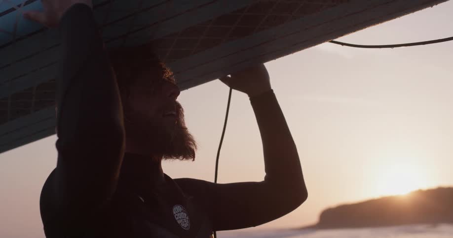 Man is holding a surfboard sun is going down