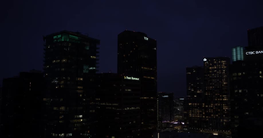 Lights illuminate from glass city building windows