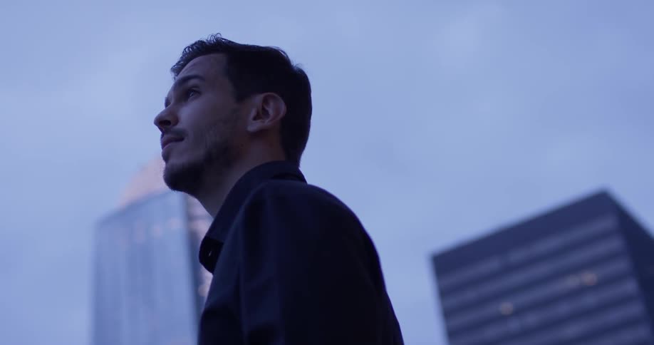 A man looking around a city at dusk