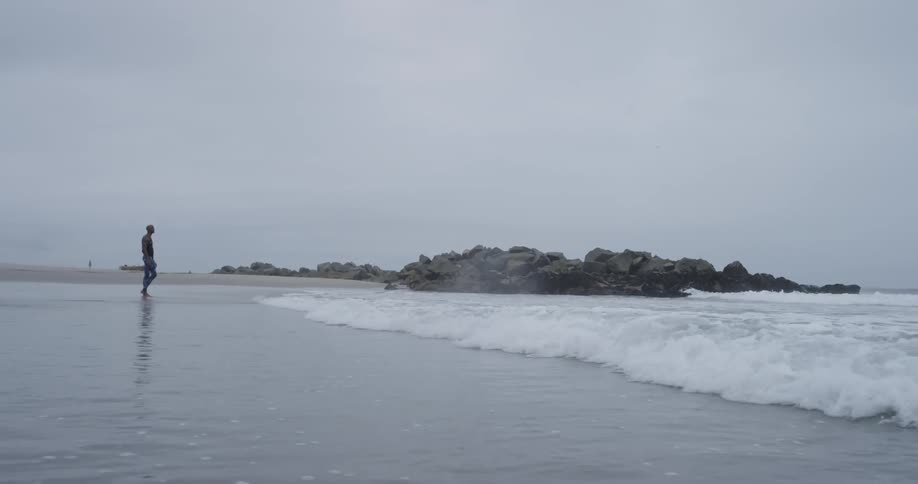 A man standing in the ocean next to waves