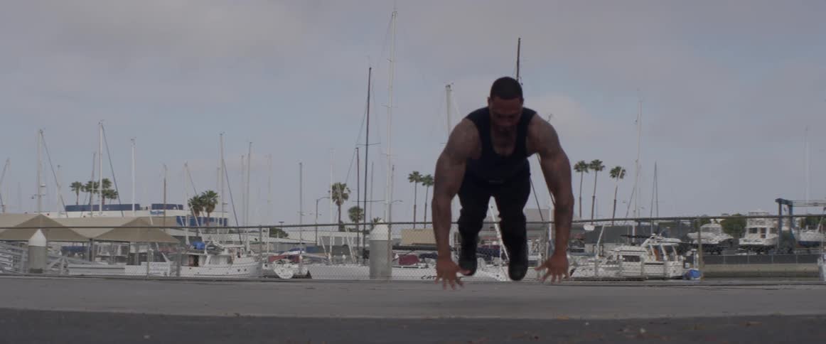 A man doing push ups with his fists jumps up into the air and side to side