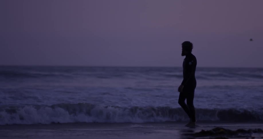 A man walking along the coast kicking water