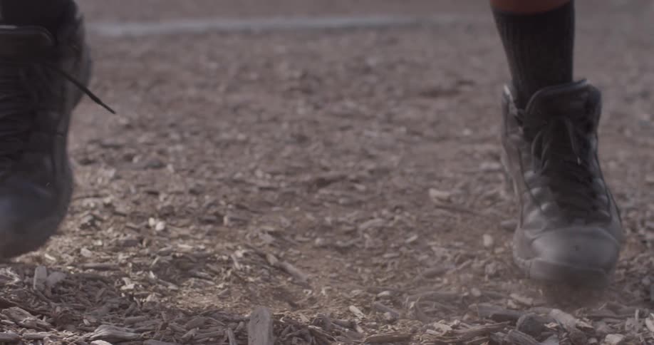 Someone's feet move across mulch covered ground
