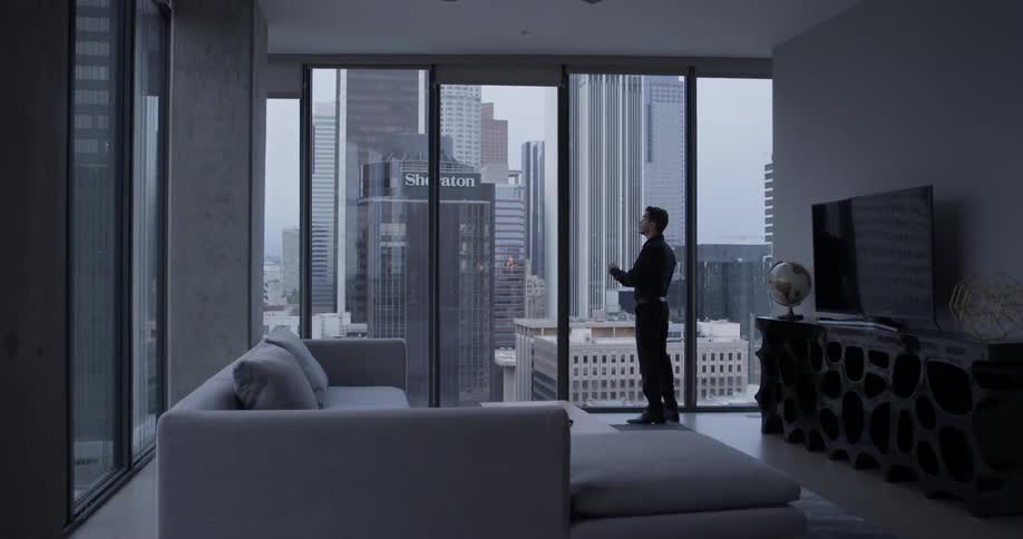 A man walks across the room and touches his face